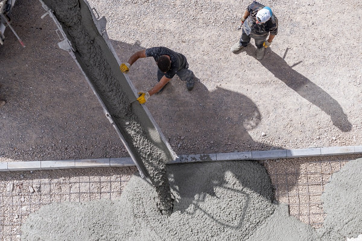 Vista dall'alto di un getto di calcestruzzo con autobetoniera in cui si vede un operatore che dirige la canala.