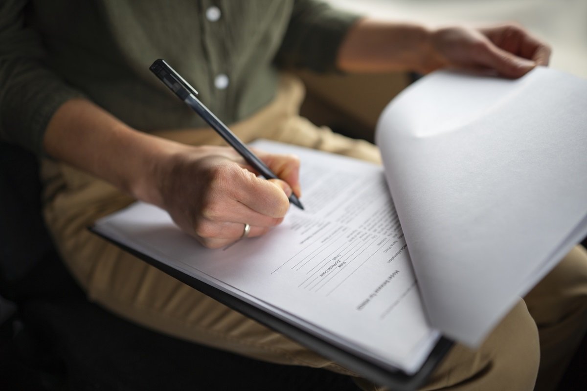 Primo piano di una mano destra femminile che compila un questionario a mano. Rappresentazione della verifica dell'efficacia della formazione sicurezza mediante somministrazione di un questionario di autovalutazione.
