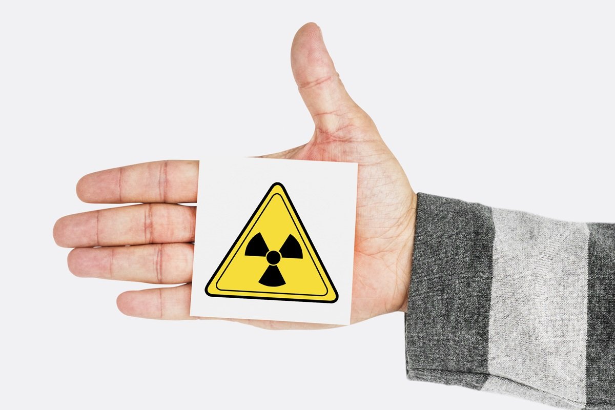 Una mano che sostiene il simbolo del pericolo di radioattività
