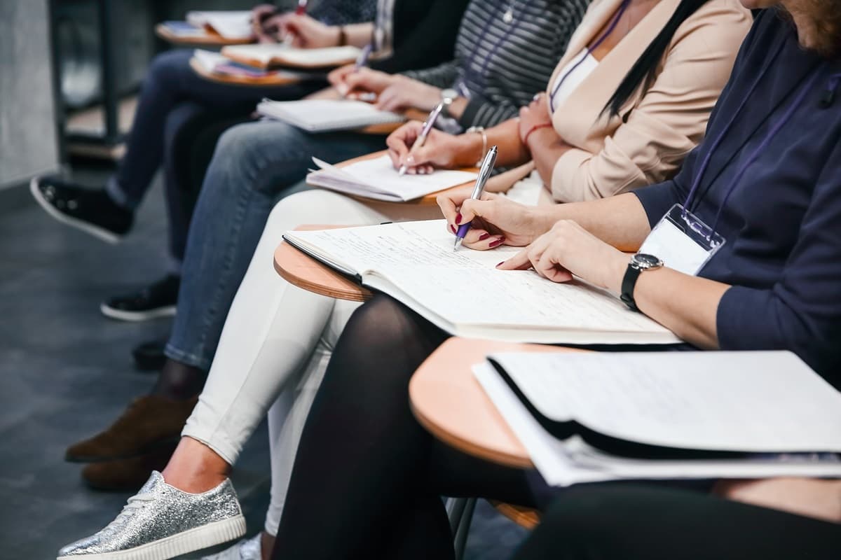 Close up di una fila di persona sedute su sedie con banco per la formazione a simboleggiare una delle principali novità dell'edizione 2025 dello standard ISO 37001.